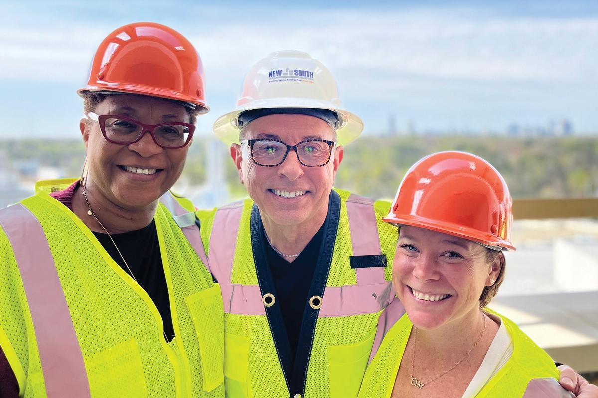 three people wearing hard hats and smiling to the camera.