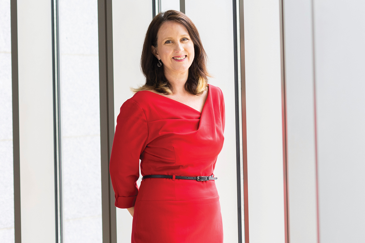 a portrait of a woman wearing a red dress and standing 