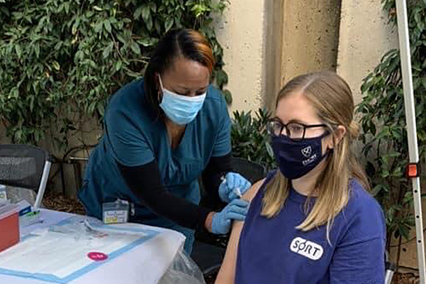 A woman receives a vaccine from a healthcare professional