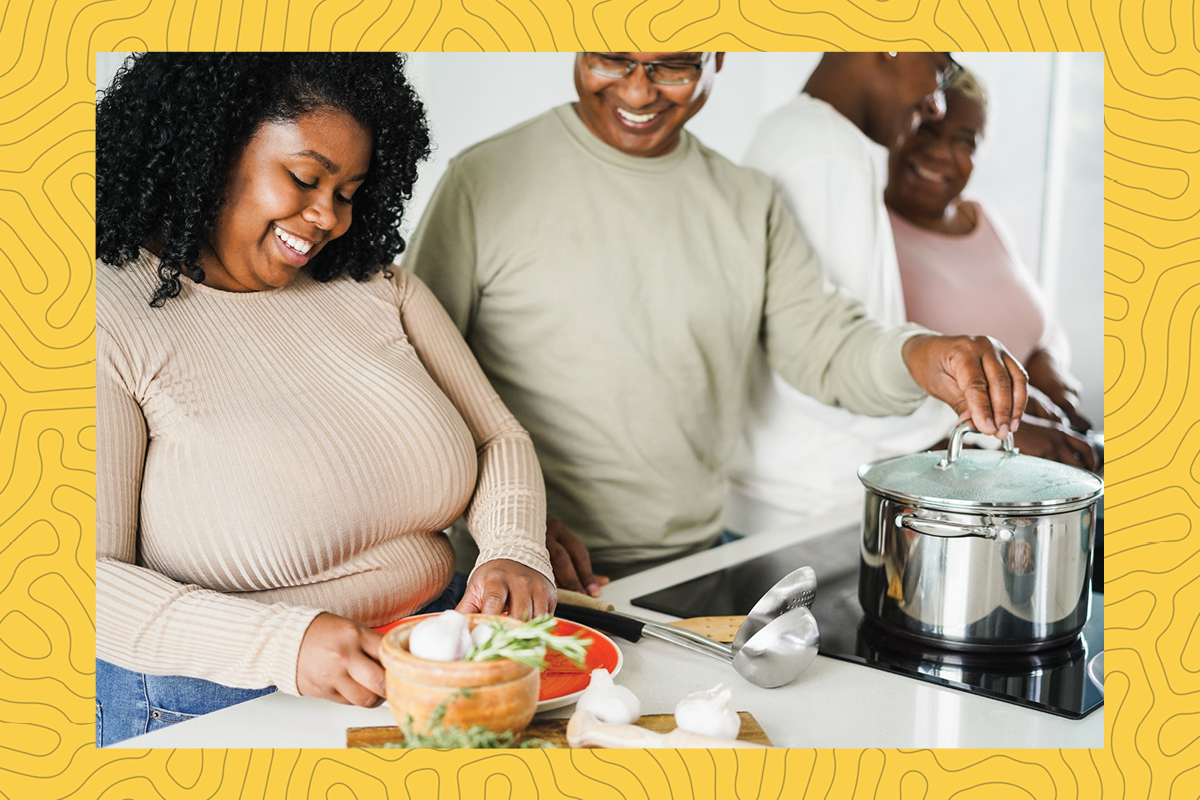 a stock photograph of a black family cooking a healthy meal together.